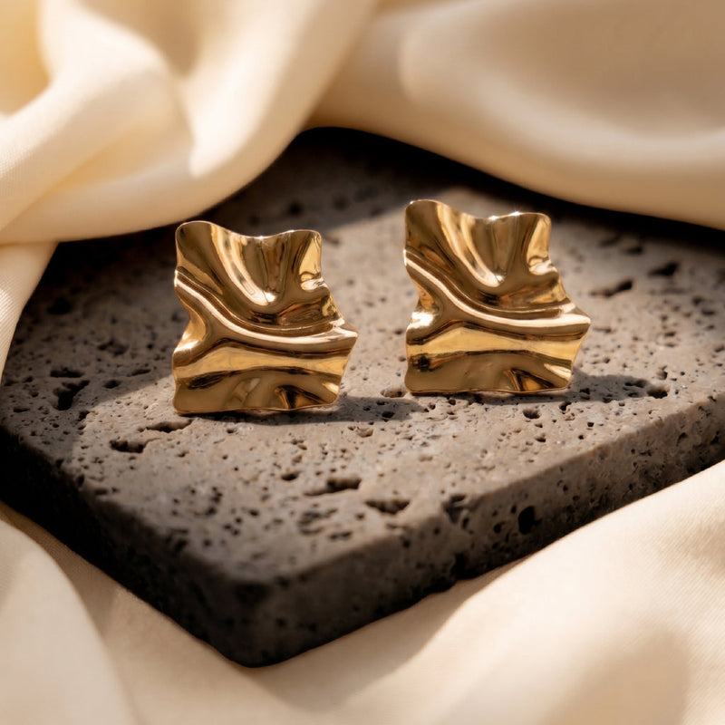 A pair of gold teardrop stud earrings with turquoise-blue stones with caption Jewellery that empowers you