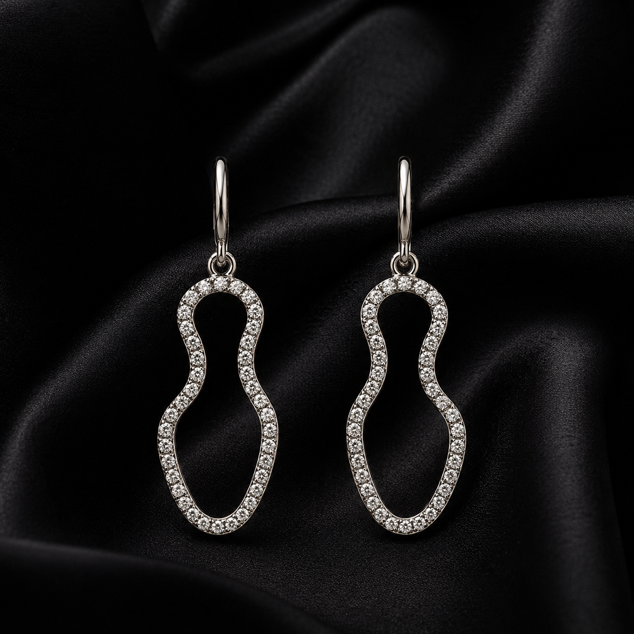 Pair of Aura Wave Drop earrings on a black satin fabric