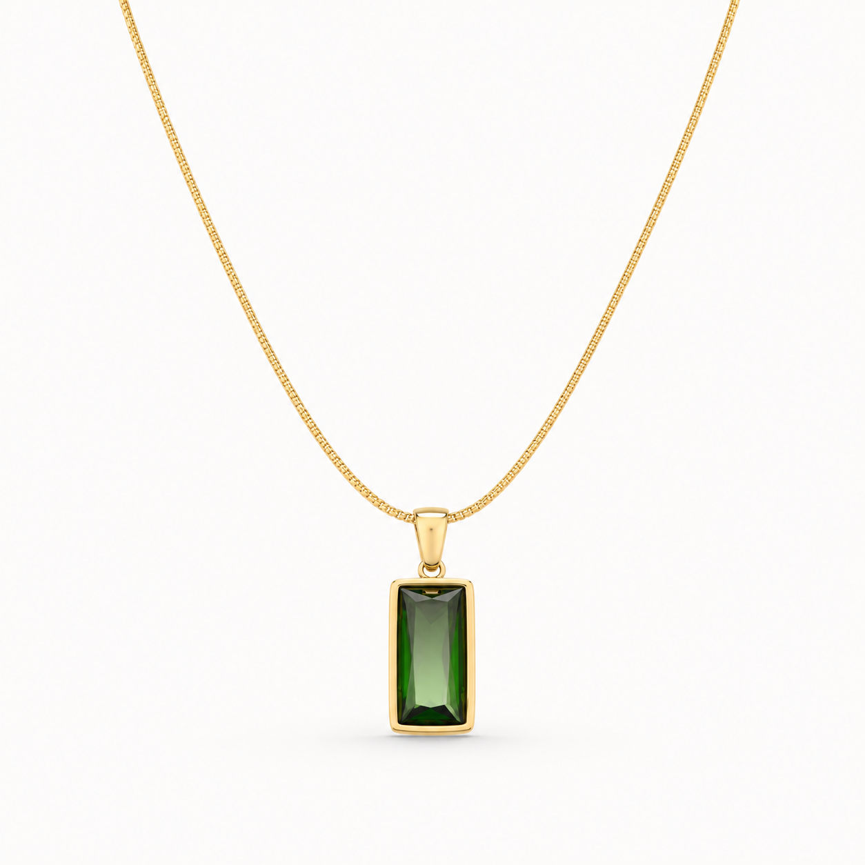 Gold necklace with a green gemstone pendant on a white background