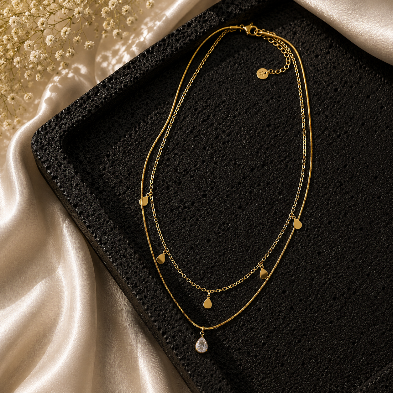 Layered Teardrop Pendant on a textured black stone tray 